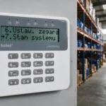 Manipulator LCD systemu alarmowego zamontowany na ścianie w hali magazynowej
